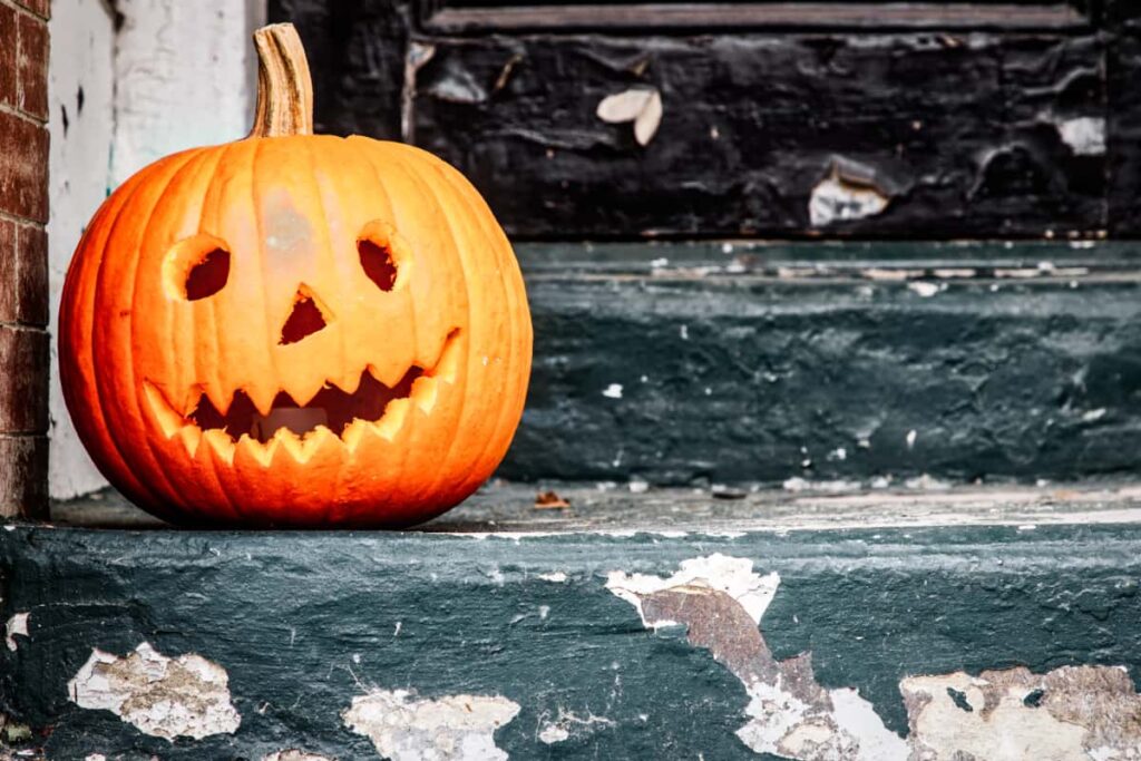 A carved Jack-O-Lantern sits on a poorly-maintained staircase.